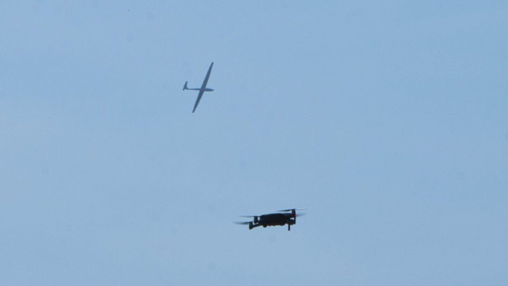 Segelflugzeug am Himmel mit Drohne im Vordergrund