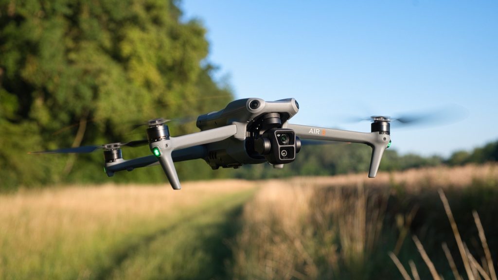 DJI Air 3 fliegt vor einem Feld in der Schrägansicht