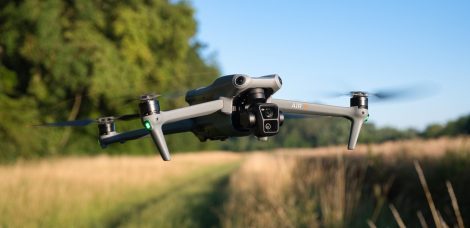 DJI Air 3 fliegt vor einem Feld in der Schrägansicht