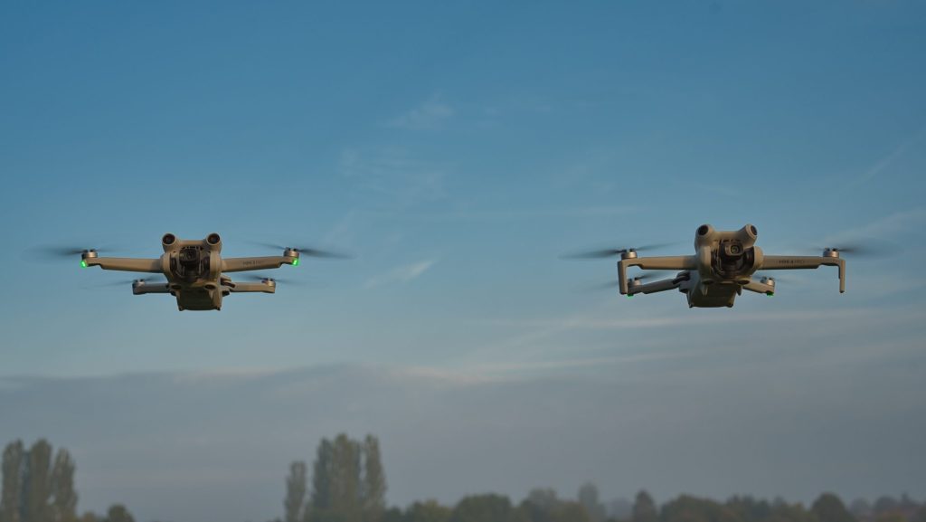 DJI Mini 4 Pro und DJI Mini 3 Pro - Schweben nebeneinander vor blaumem Himmel