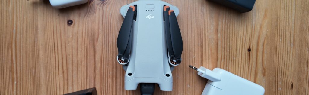 Mehrere USB PD Netzteile liegen um eine DJI Mini 3 Pro Drohne verteilt.